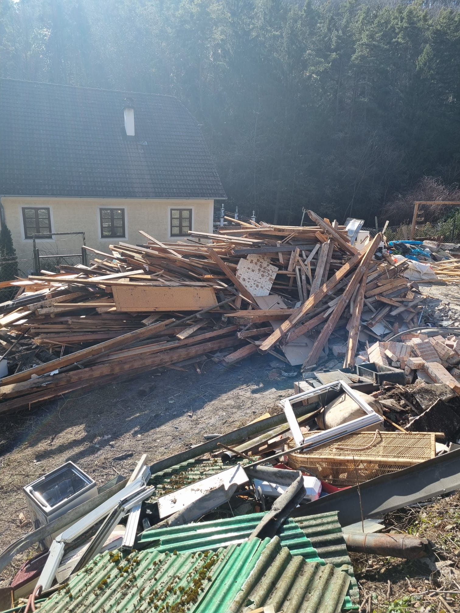 Holzlatten und Bauschutt nach dem Kleingartenhaus-Abbruch vor einem Bauernhaus